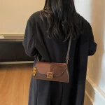 Sac à bandoulière minimaliste courbé, détail au point supérieur raffiné, Silhouette non commune pour les escapades chics, luxe sans effort