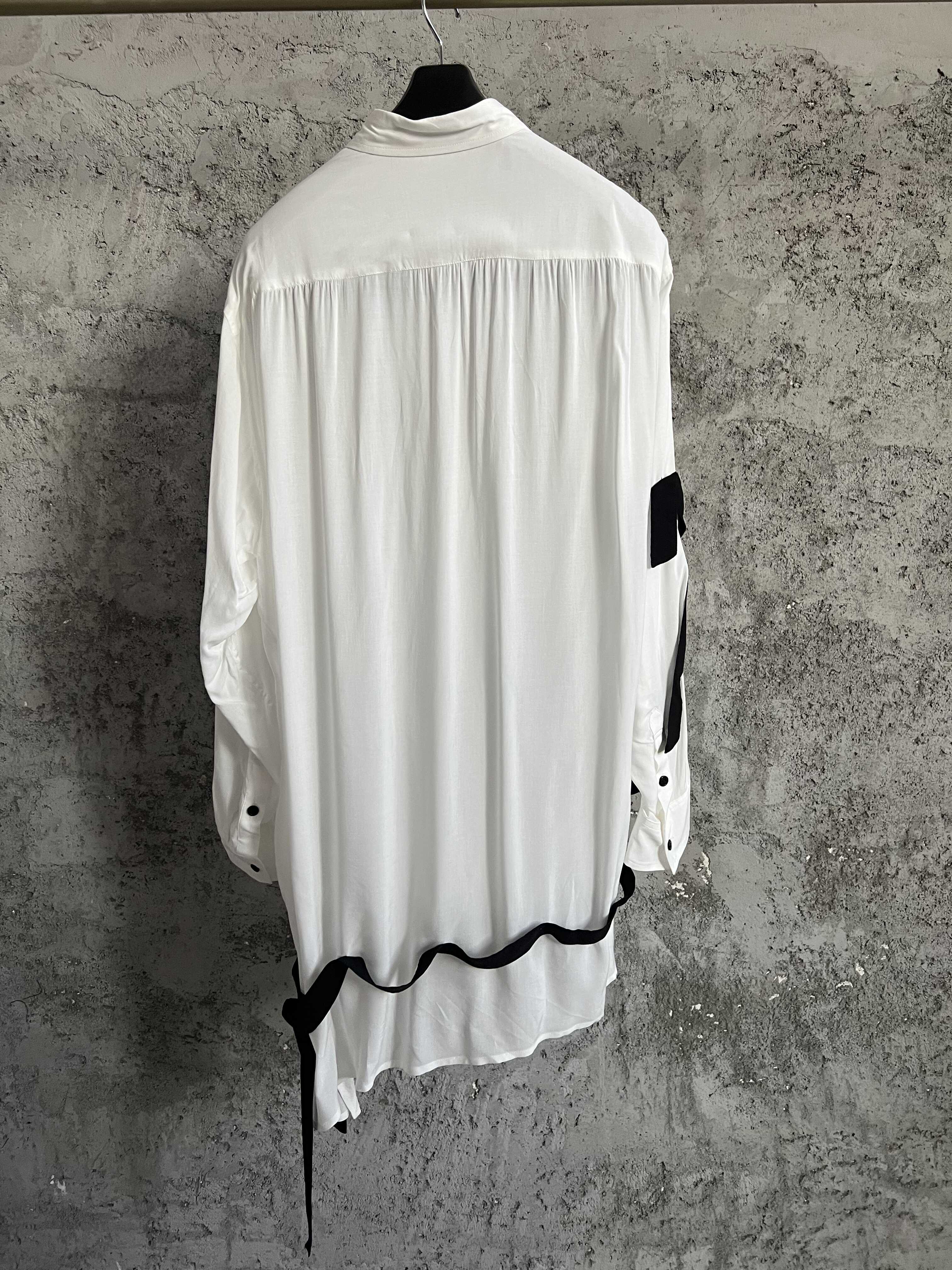 Une chemise avec des lignes de couleurs contrastées, ourlet asymétrique, style ample et fin et haut à simple boutonnage