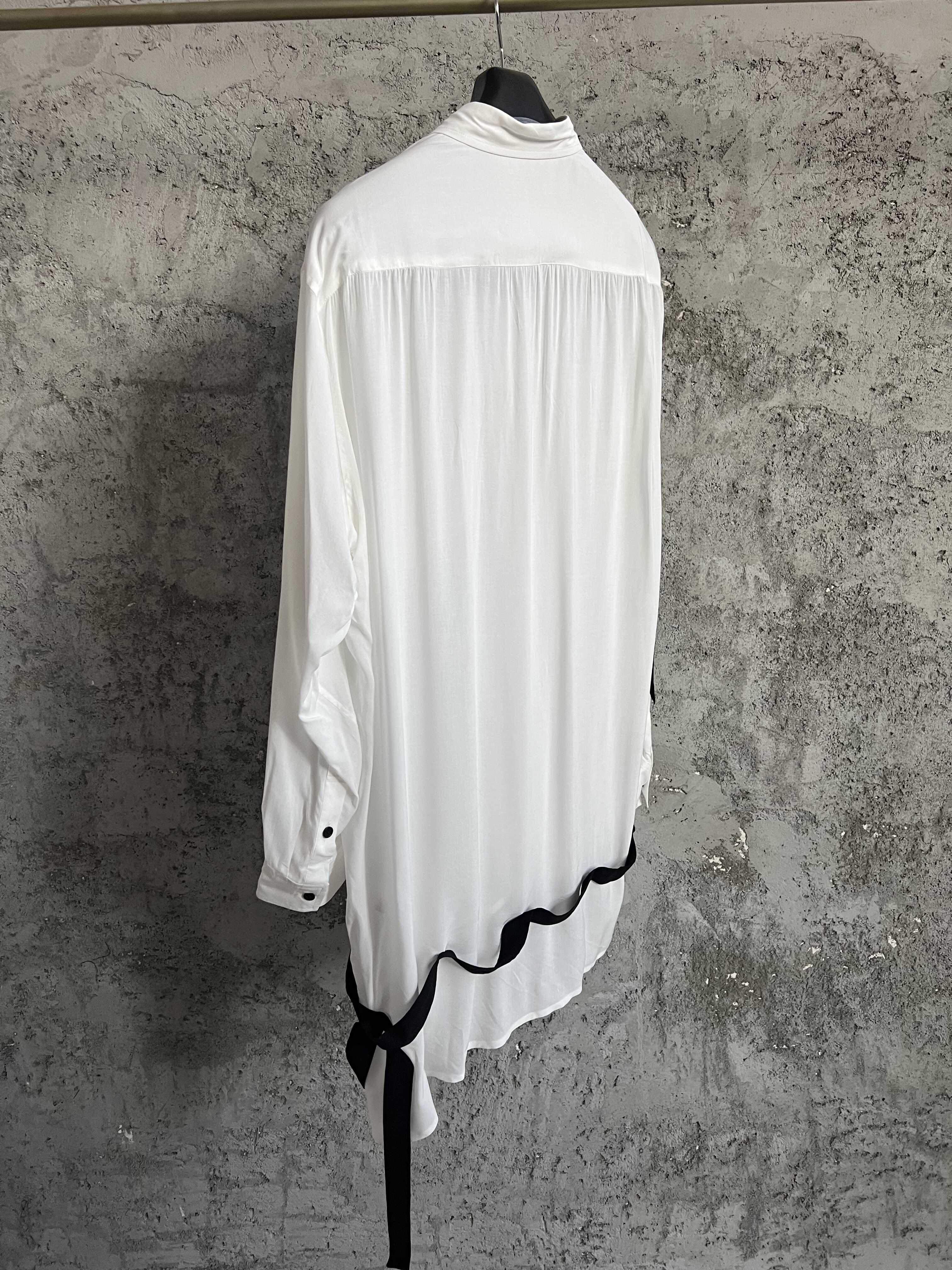 Une chemise avec des lignes de couleurs contrastées, ourlet asymétrique, style ample et fin et haut à simple boutonnage