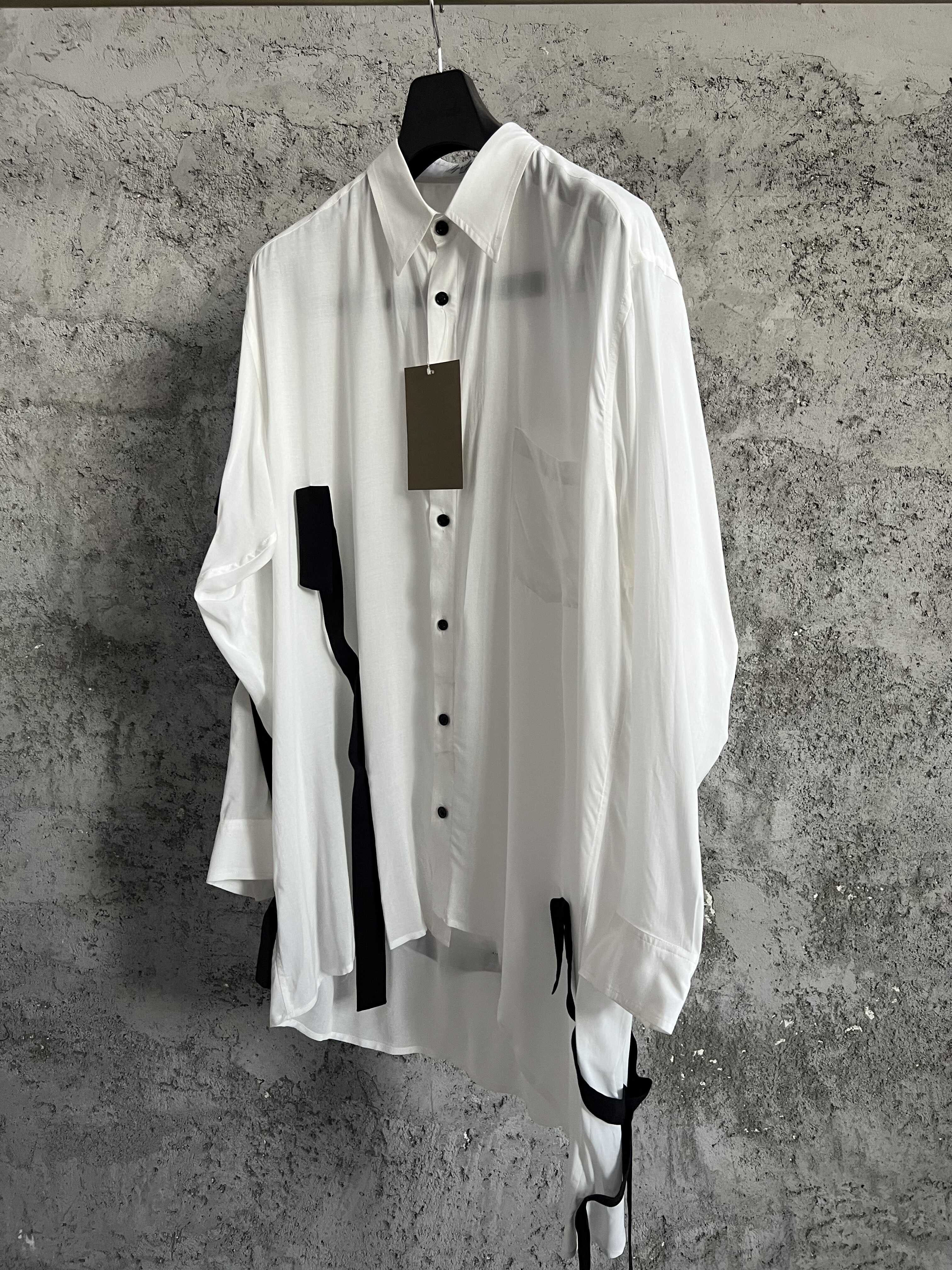 Une chemise avec des lignes de couleurs contrastées, ourlet asymétrique, style ample et fin et haut à simple boutonnage