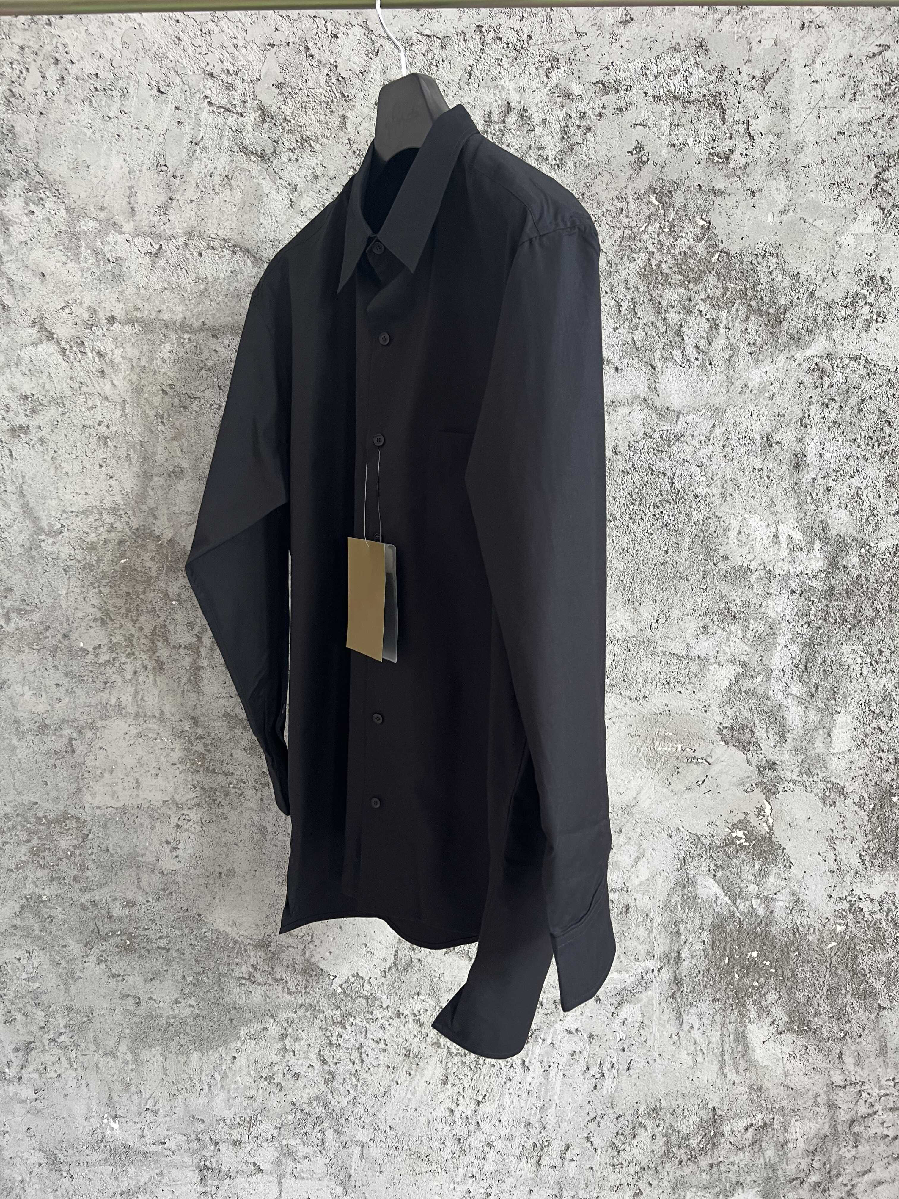 Une simple chemise simple boutonnage à manches longues avec un col double couche, couleur unie et design asymétrique