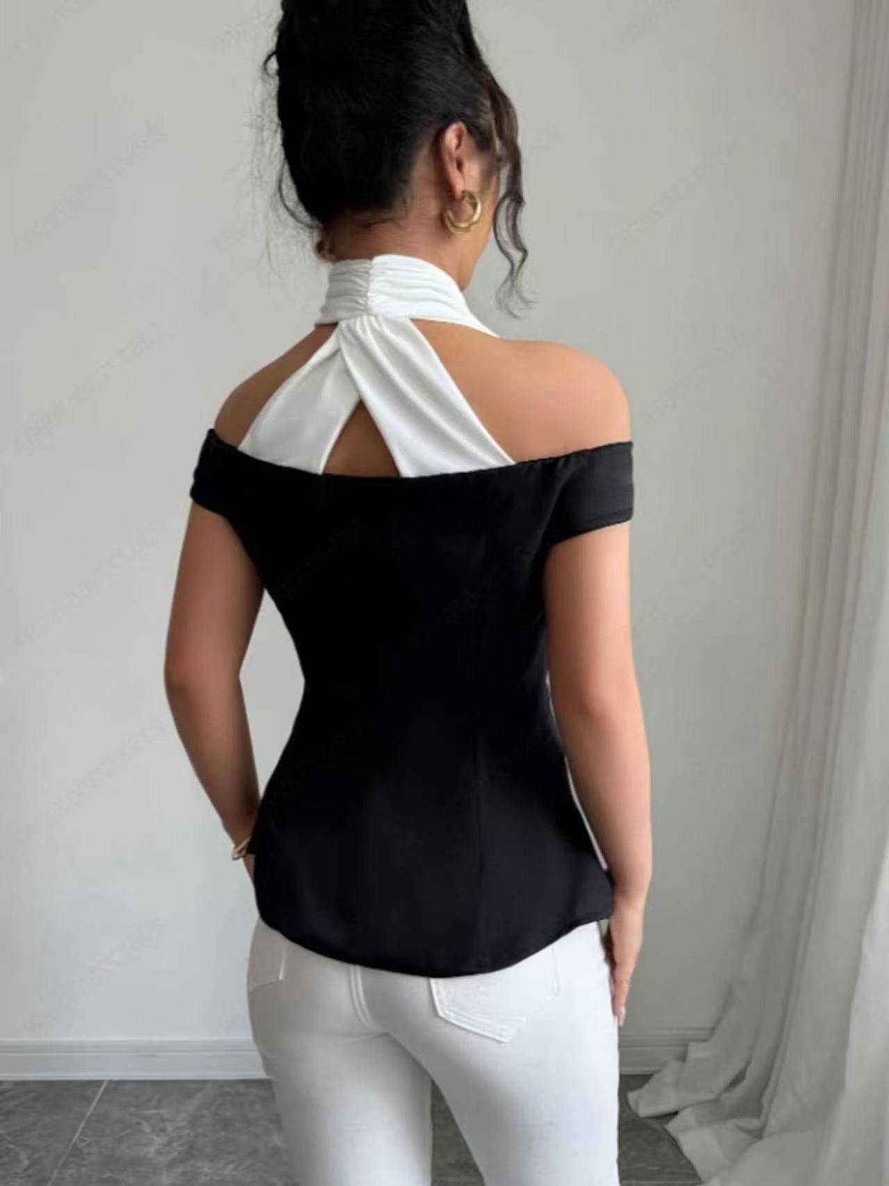 Blouse élégante noire et blanche à blocs de couleur, col halter, épaules dénudées, dos ouvert croisé, taille cintrée boutonnée, coupe ajustée courte pour femme