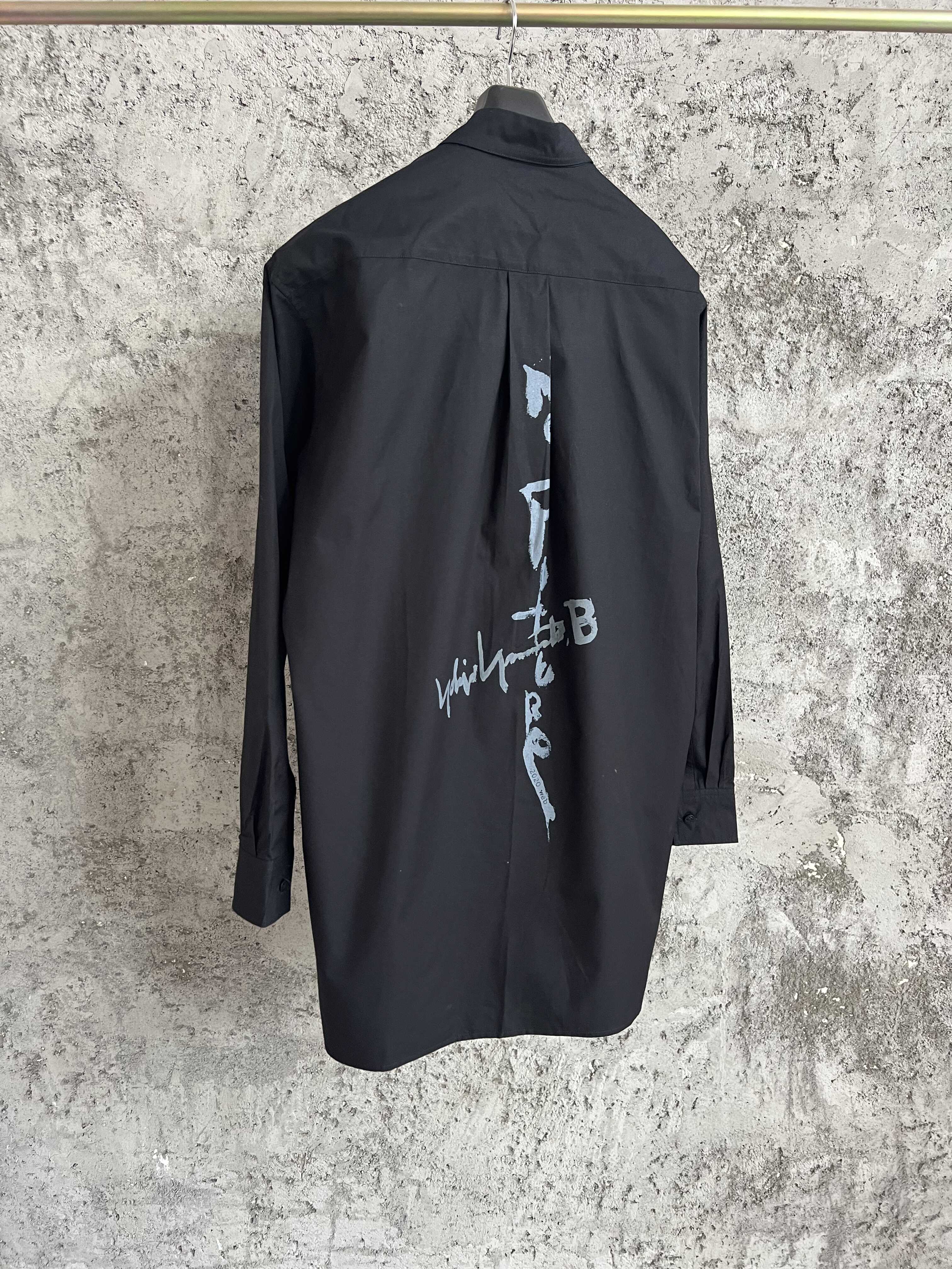 Une simple chemise simple boutonnage à manches longues avec un col double couche, couleur unie et design asymétrique