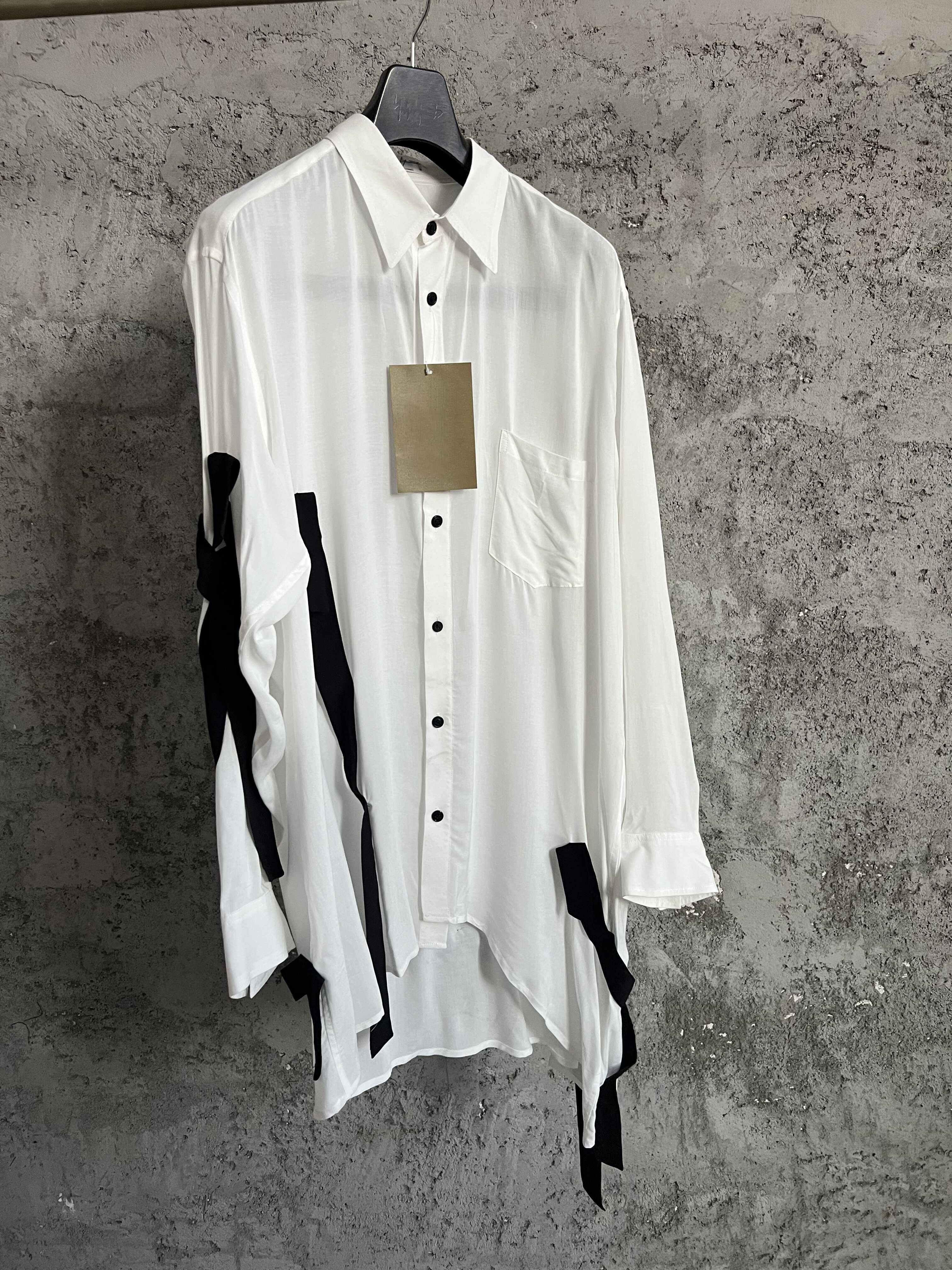 Une chemise avec des lignes de couleurs contrastées, ourlet asymétrique, style ample et fin et haut à simple boutonnage