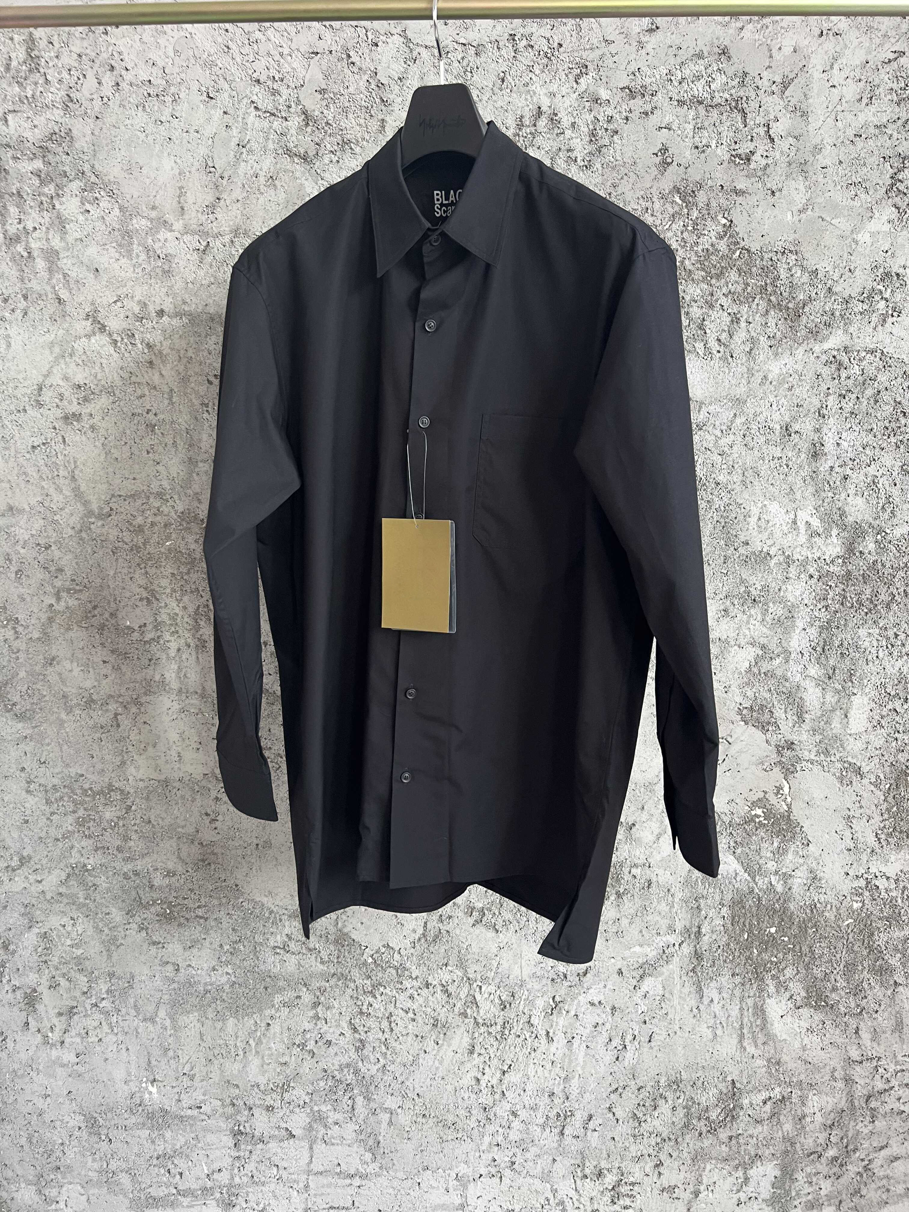 Une simple chemise simple boutonnage à manches longues avec un col double couche, couleur unie et design asymétrique